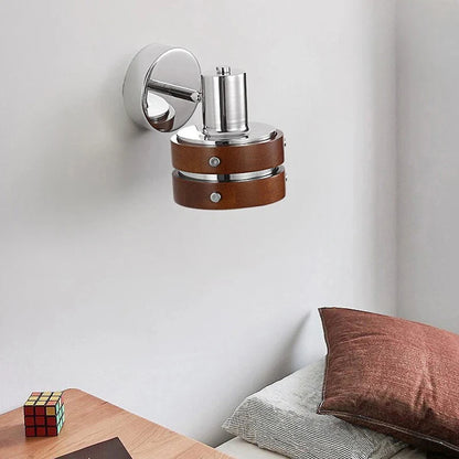 Adjustable wall spotlight in chrome and brown above a bed