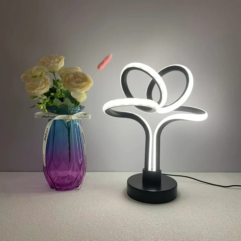 Black LED loop table lamp beside a vase