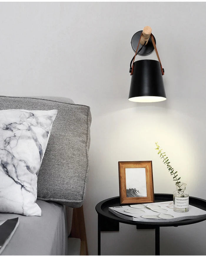 Scandinavian wall lamp with wooden arm next to a bed